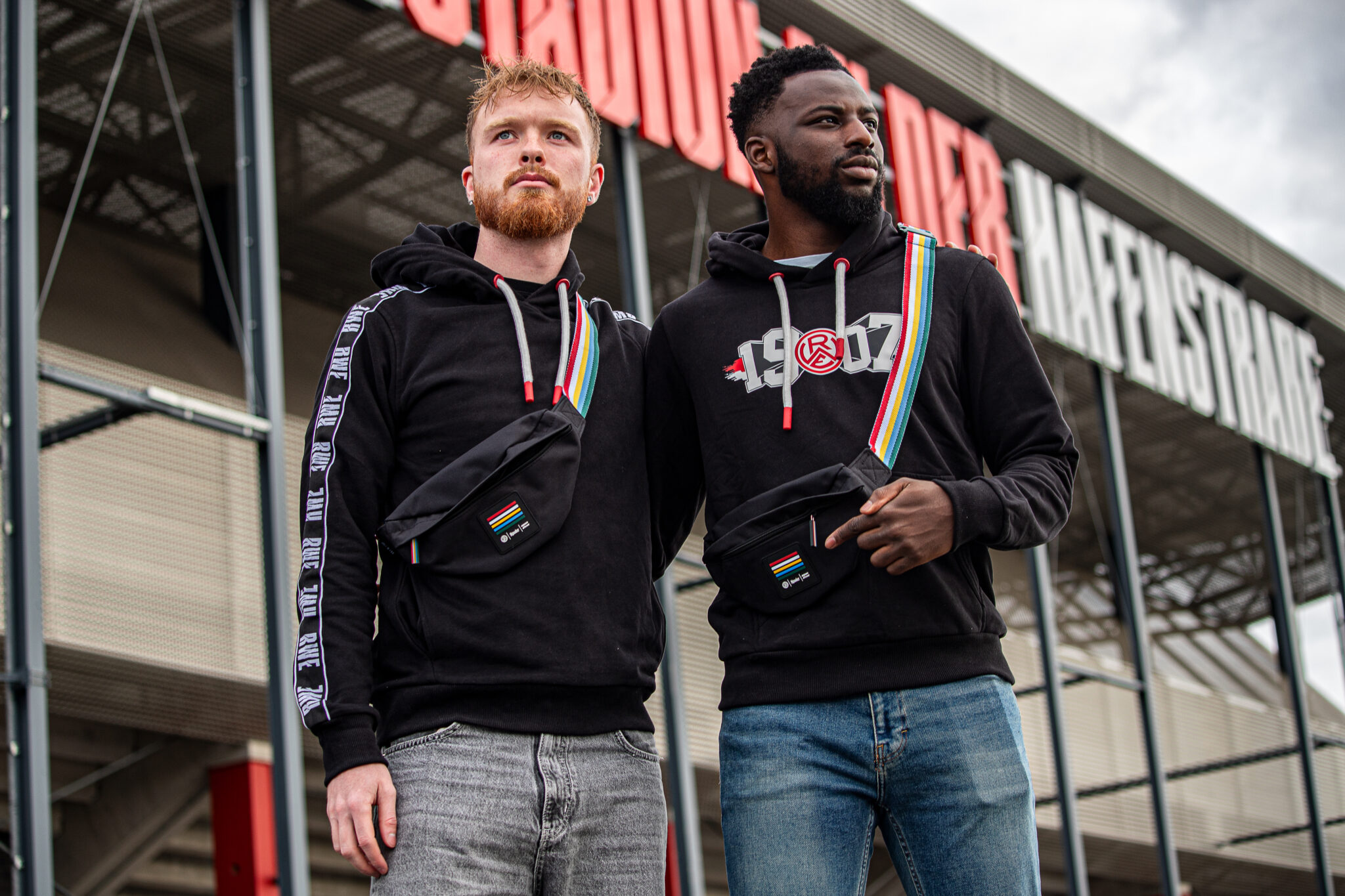 Die Rot-Weiss Essen-Spieler Fabian Rüth (l.) und Mustafa Kourouma präsentieren die neue Bauchtasche.